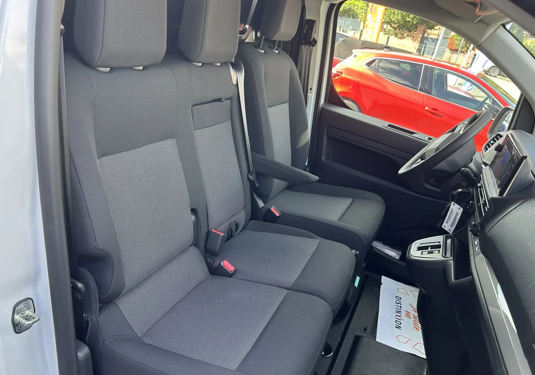 Vue intérieure côté conducteur du Citroën Jumpy blanc 2025, montrant les sièges avant en tissu gris et noir.