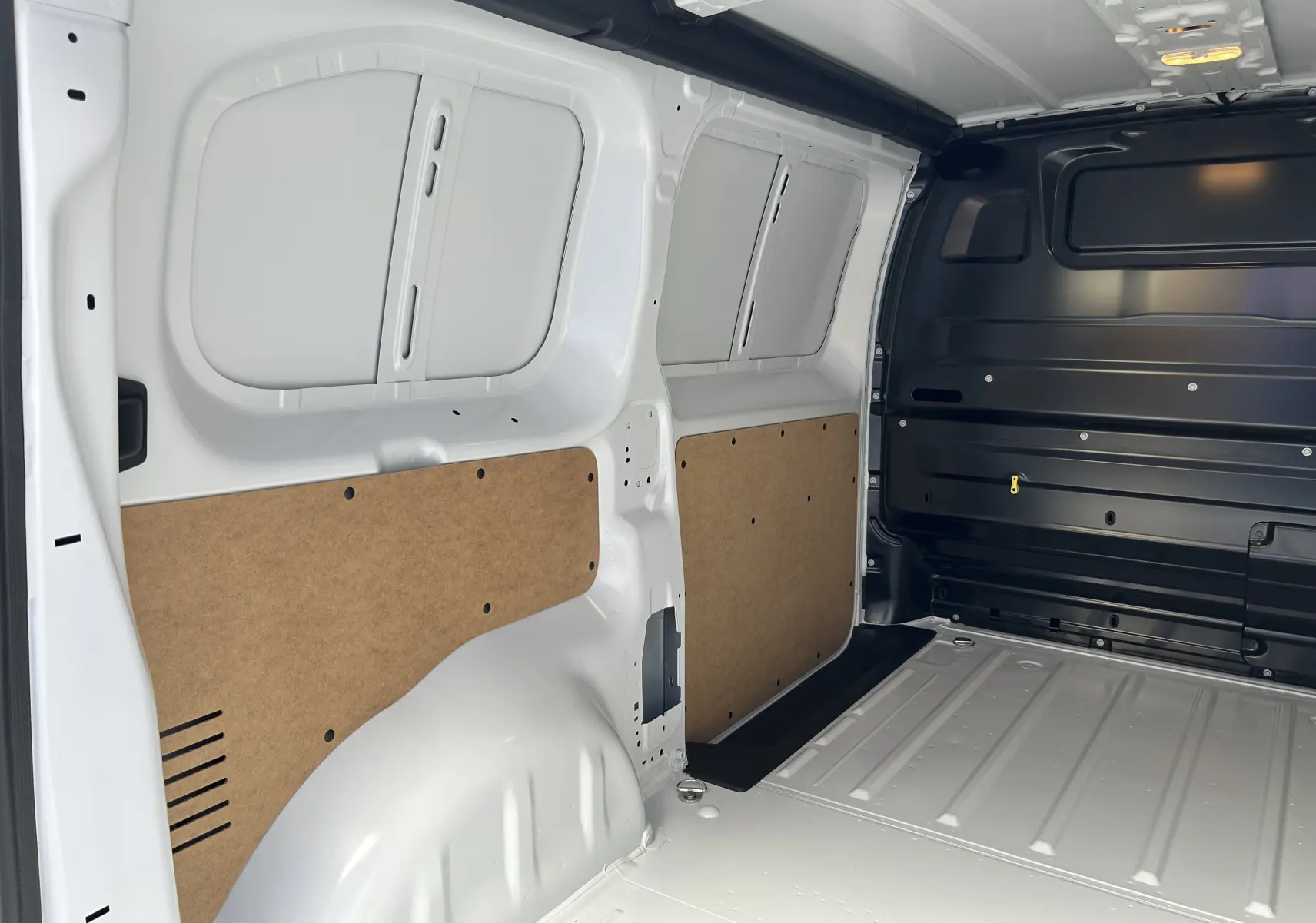 Vue intérieure arrière du fourgon blanc Citroën Jumpy 2025, montrant la paroi latérale avec panneaux de protection en bois.