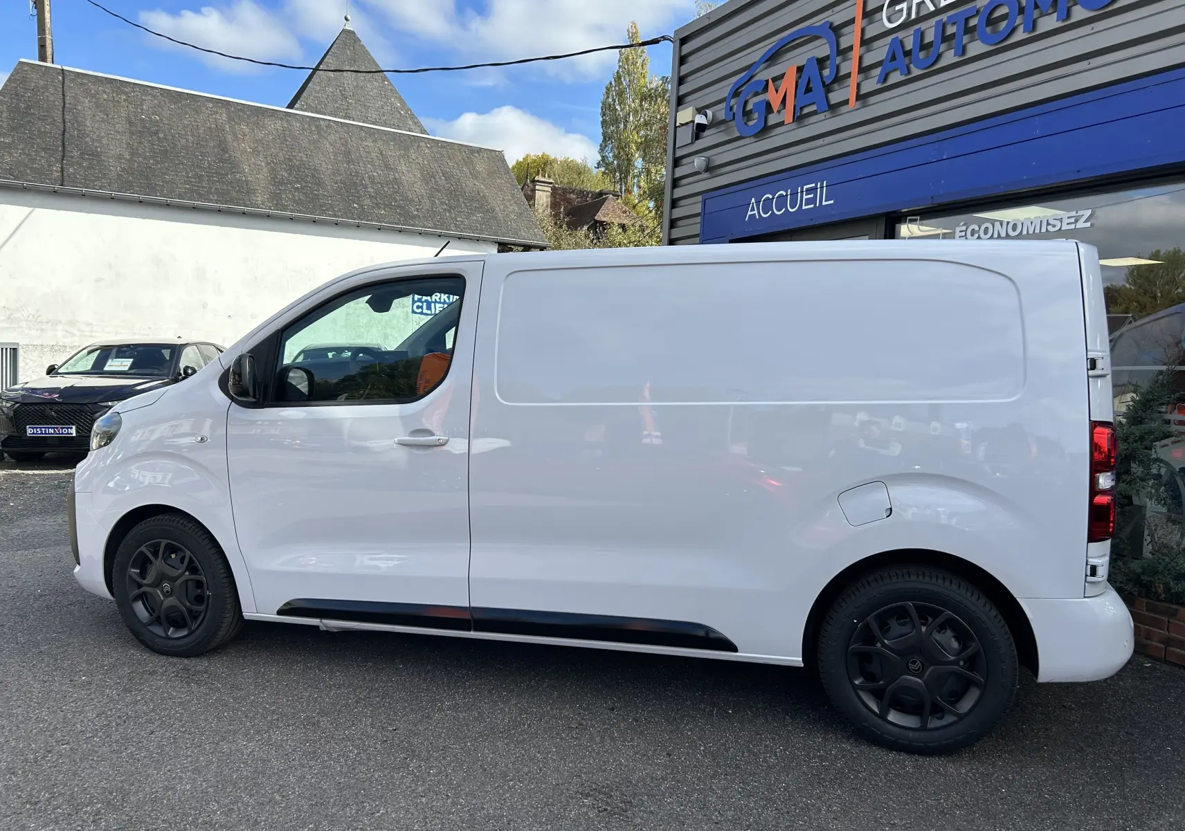 Vue de profil côté gauche d’un Citroën Jumpy blanc, fourgon utilitaire avec jantes noires et porte latérale coulissante.