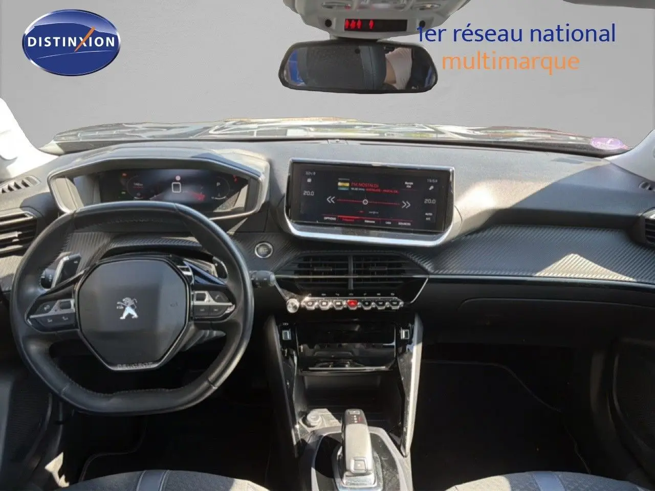 Vue intérieure avant du tableau de bord et volant noir de la Peugeot 2008 gris platinium avec écran tactile central et commandes modernes.