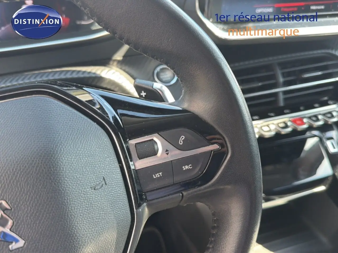 Gros plan sur le volant cuir noir de la Peugeot 2008 1.2 PureTech 130 Allure avec commandes intégrées et tableau de bord moderne.