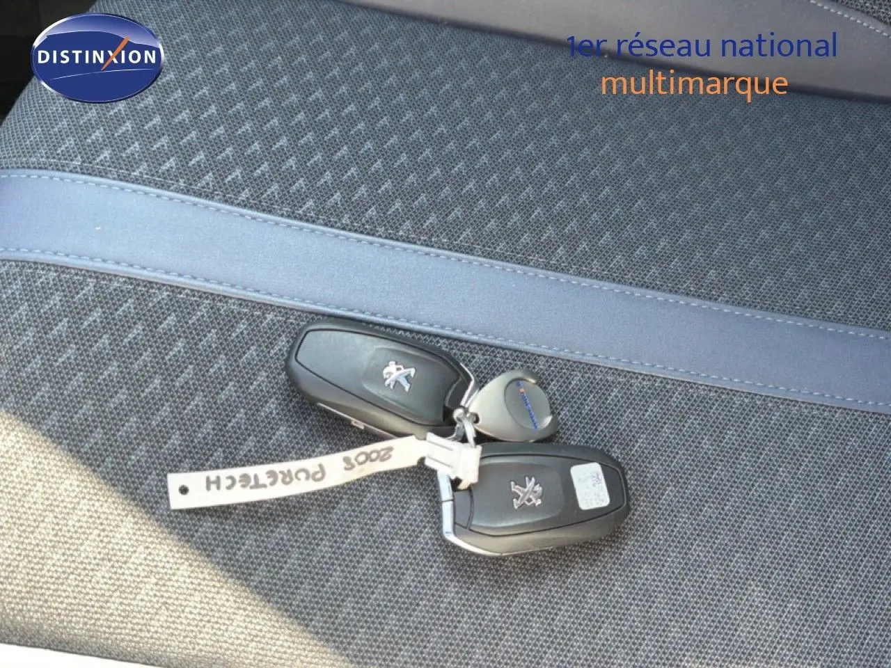 Je vois que l'image montre uniquement des clés de voiture posées sur un siège, sans vue du véhicule lui-même. Voici une description alt adaptée :

Clés de Peugeot 2008 posées sur un siège en tissu gris, sans vue du véhicule