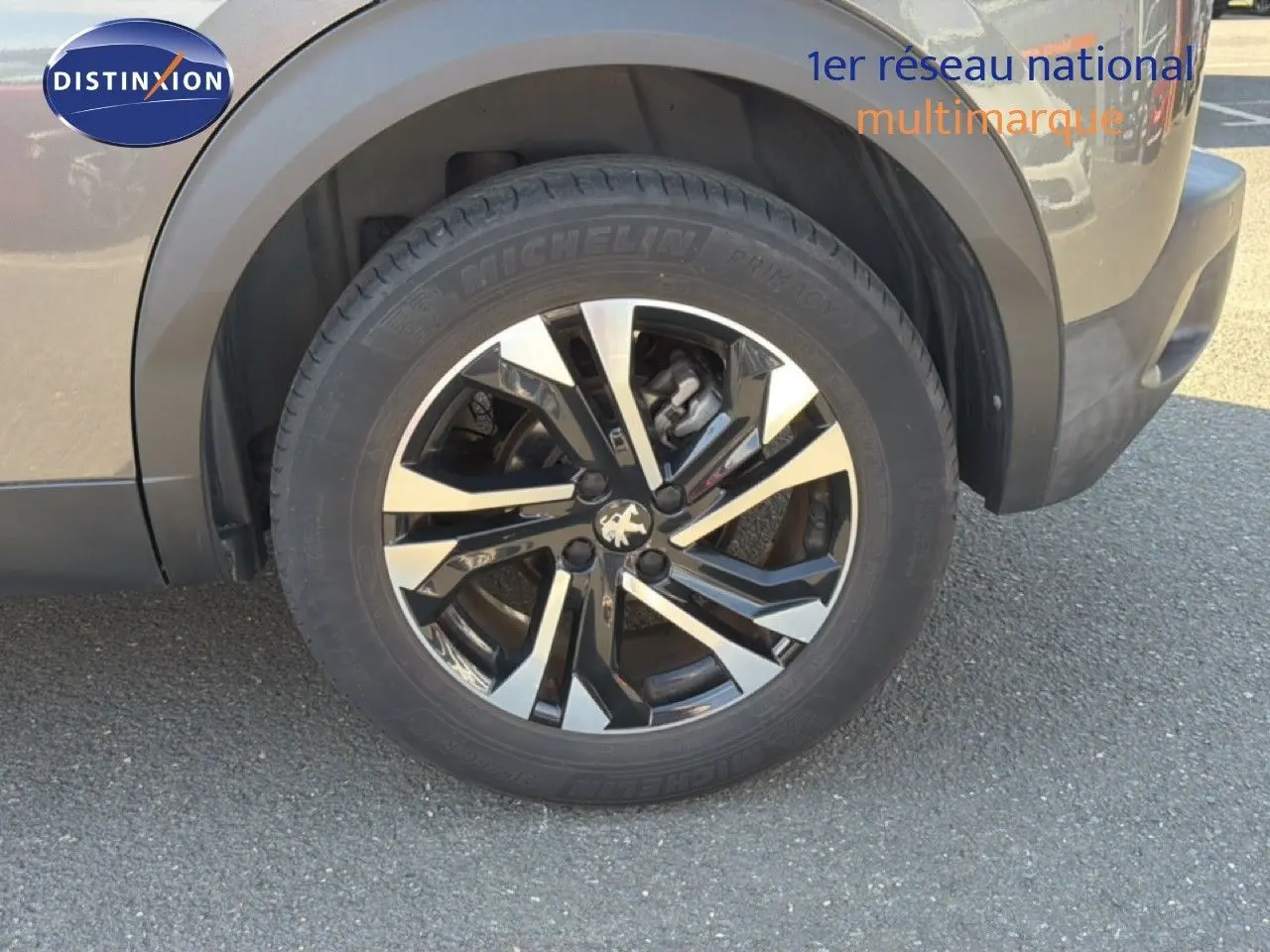 Gros plan sur la roue avant gauche avec jante alliage bicolore et carrosserie gris platinium du Peugeot 2008 2020.