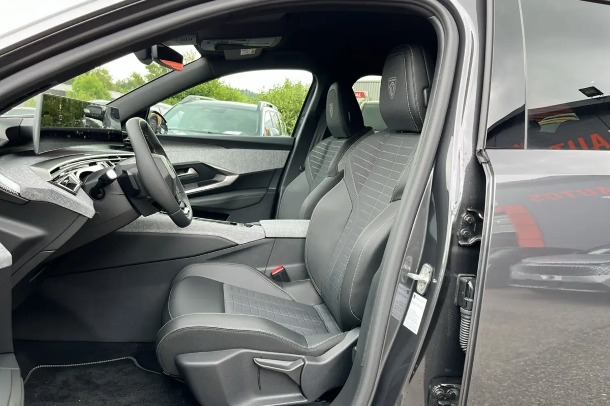 Vue intérieure côté conducteur du Peugeot 5008 gris titane avec sièges en cuir et tissu, volant multifonctions et tableau de bord moderne.