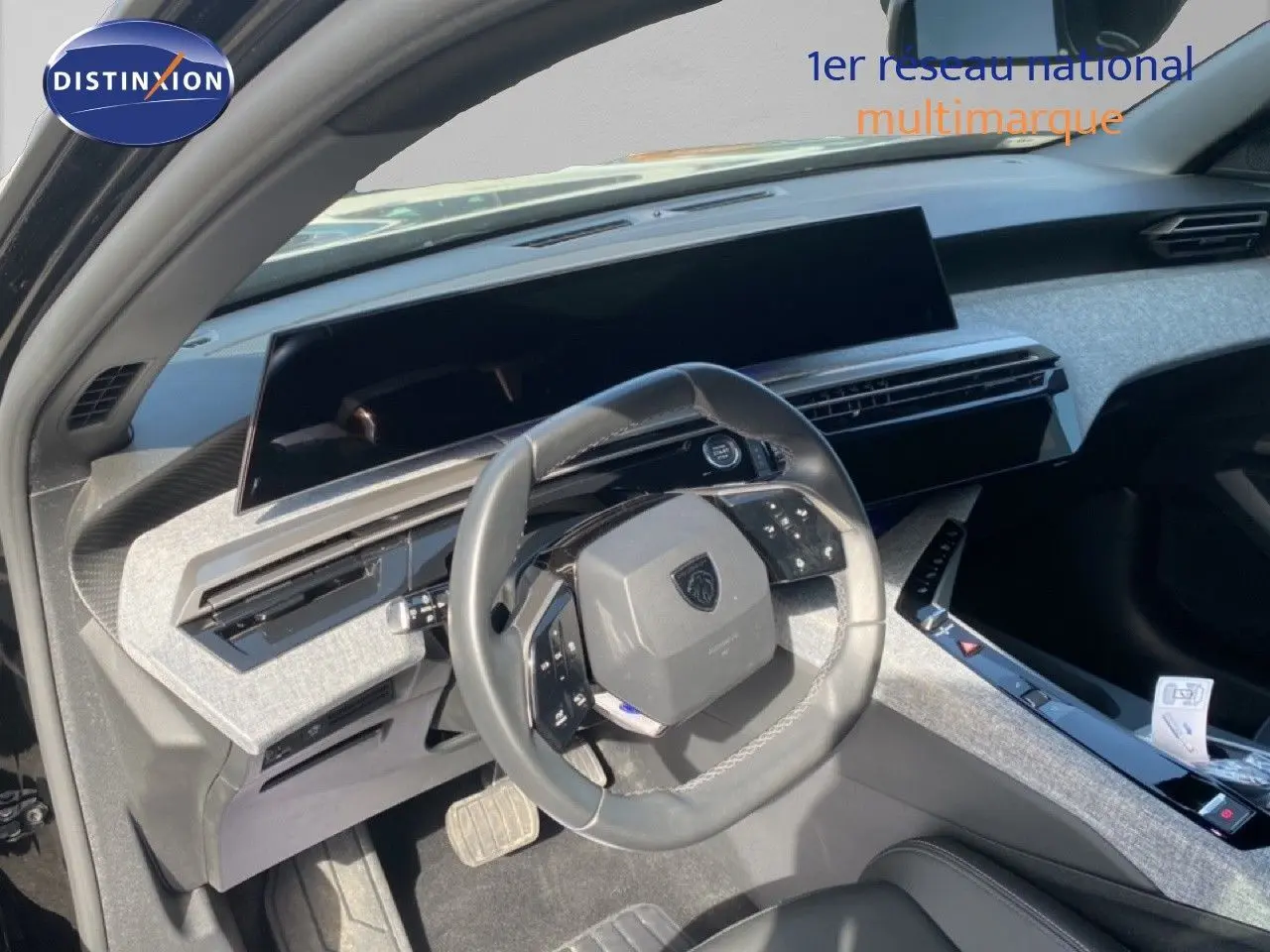 Vue intérieure côté conducteur du Peugeot 5008 Hybrid 2025, volant multifonction et tableau de bord moderne gris clair.