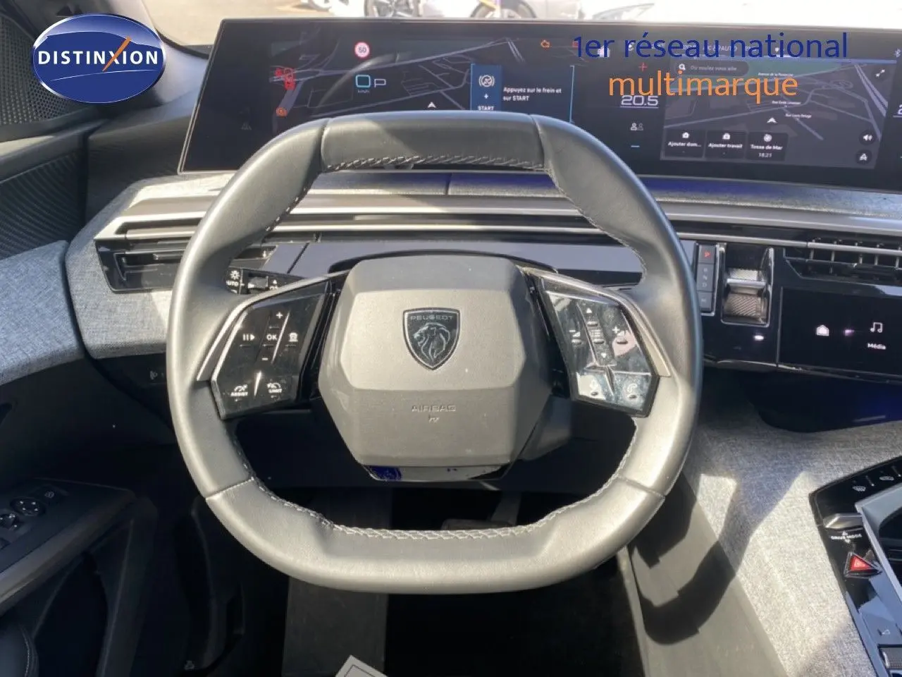 Vue rapprochée du volant cuir noir du Peugeot 5008 Hybrid 145ch 2025 avec tableau de bord numérique et commandes intégrées.