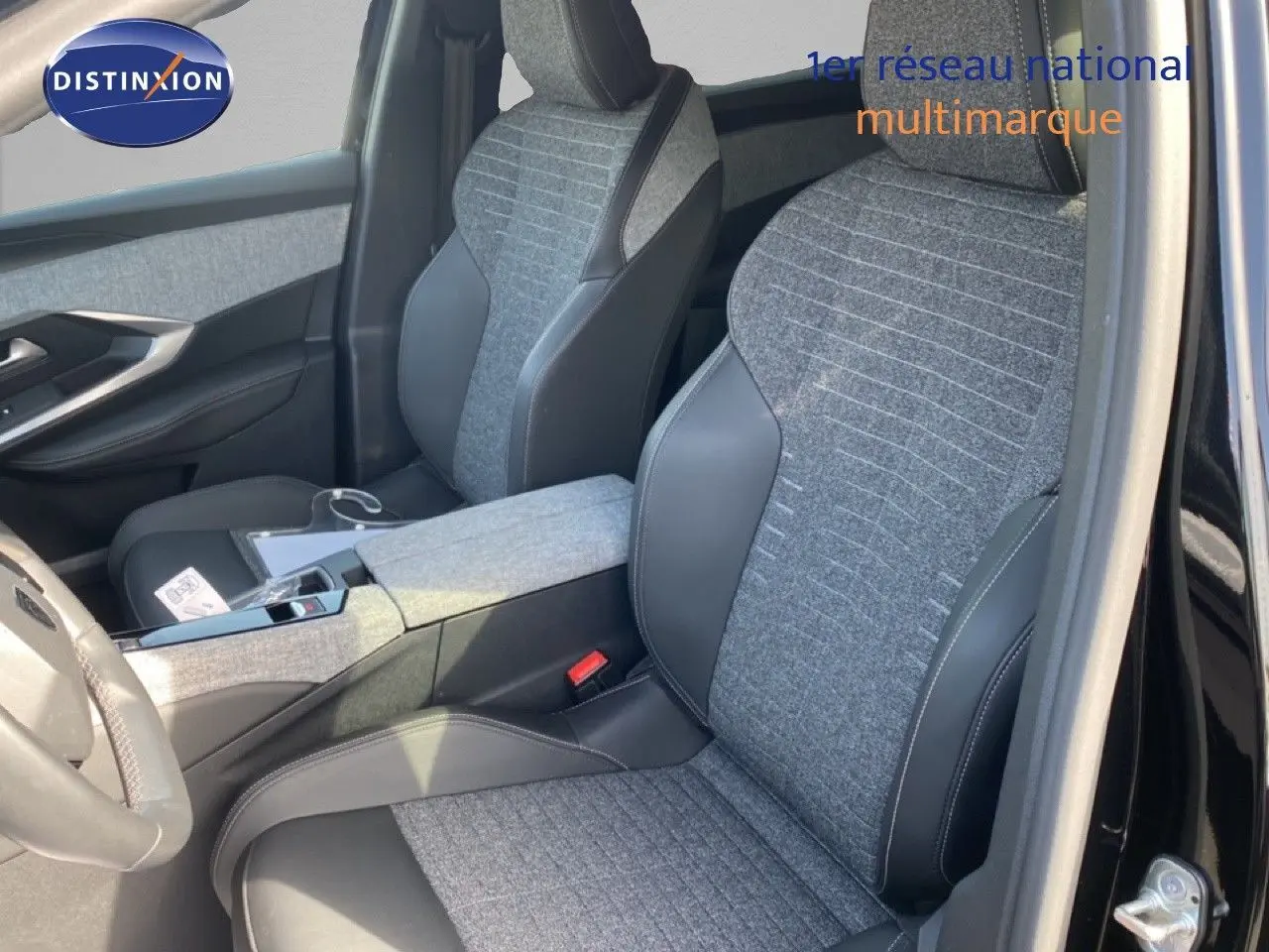Vue intérieure côté conducteur du Peugeot 5008 Hybrid 2025, sièges tissu gris et cuir noir, porte ouverte sur carrosserie noire.