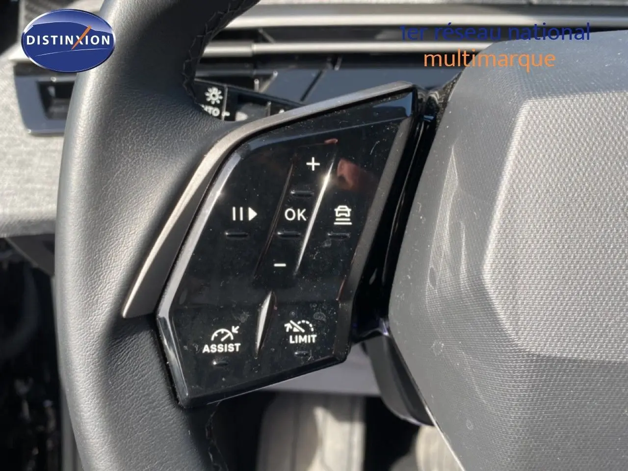 Gros plan sur les commandes au volant noir du Peugeot 5008 Hybrid 2025, avec boutons d’assistance et limitation de vitesse.