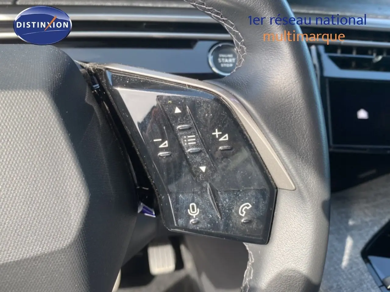 Gros plan sur les commandes au volant côté gauche du Peugeot 5008 Hybrid 2025 avec finition cuir noir et boutons multifonctions.