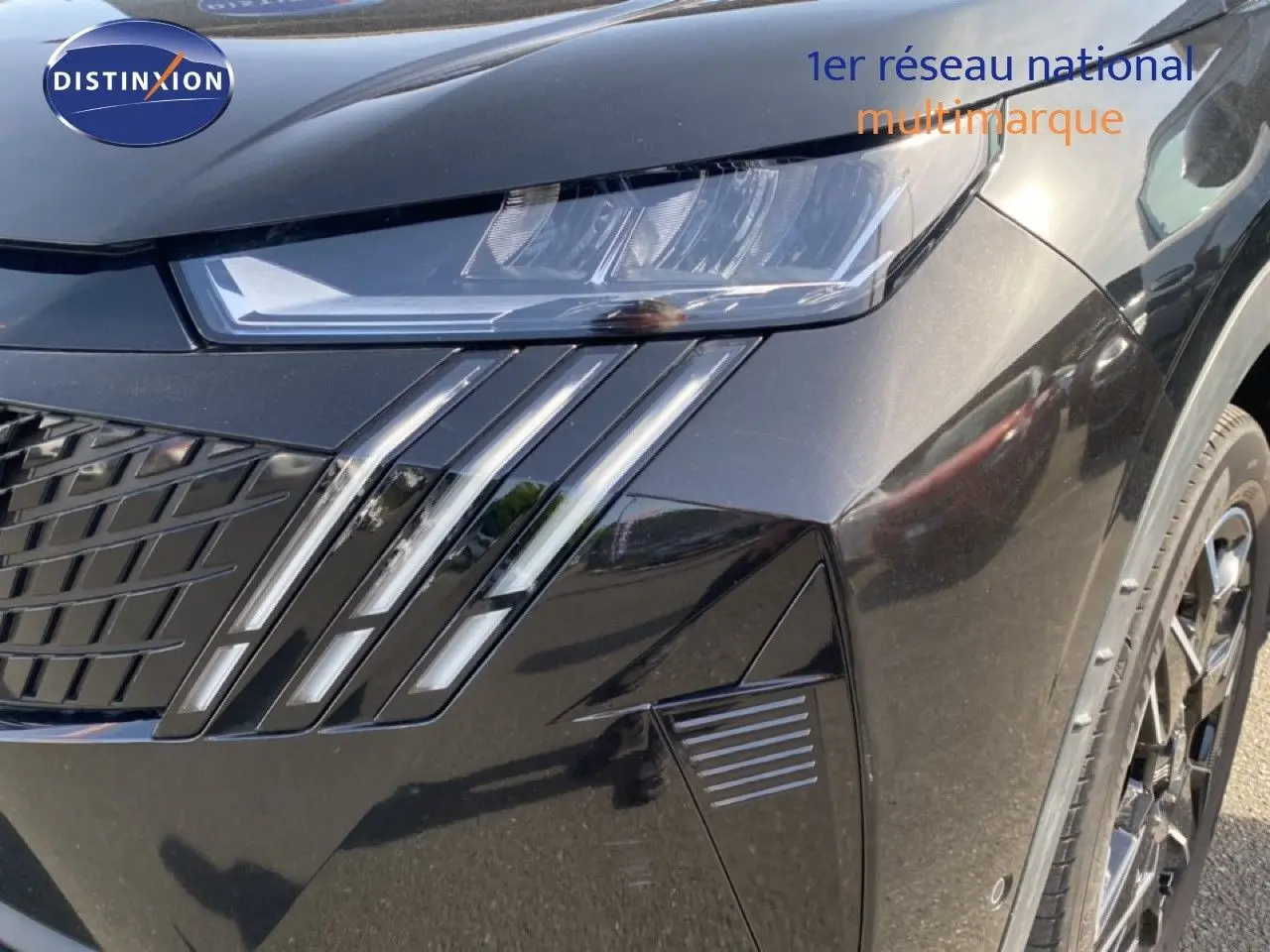 Gros plan sur l'avant droit noir Perla Nera du Peugeot 5008 Hybrid 2025, mettant en valeur le phare et la calandre distinctive.