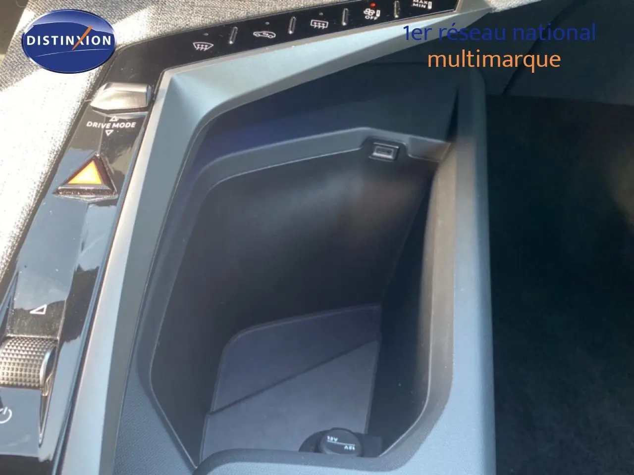 Gros plan sur la console centrale noire avec prise 12V et commandes de mode de conduite du Peugeot 5008 Hybrid 2025.