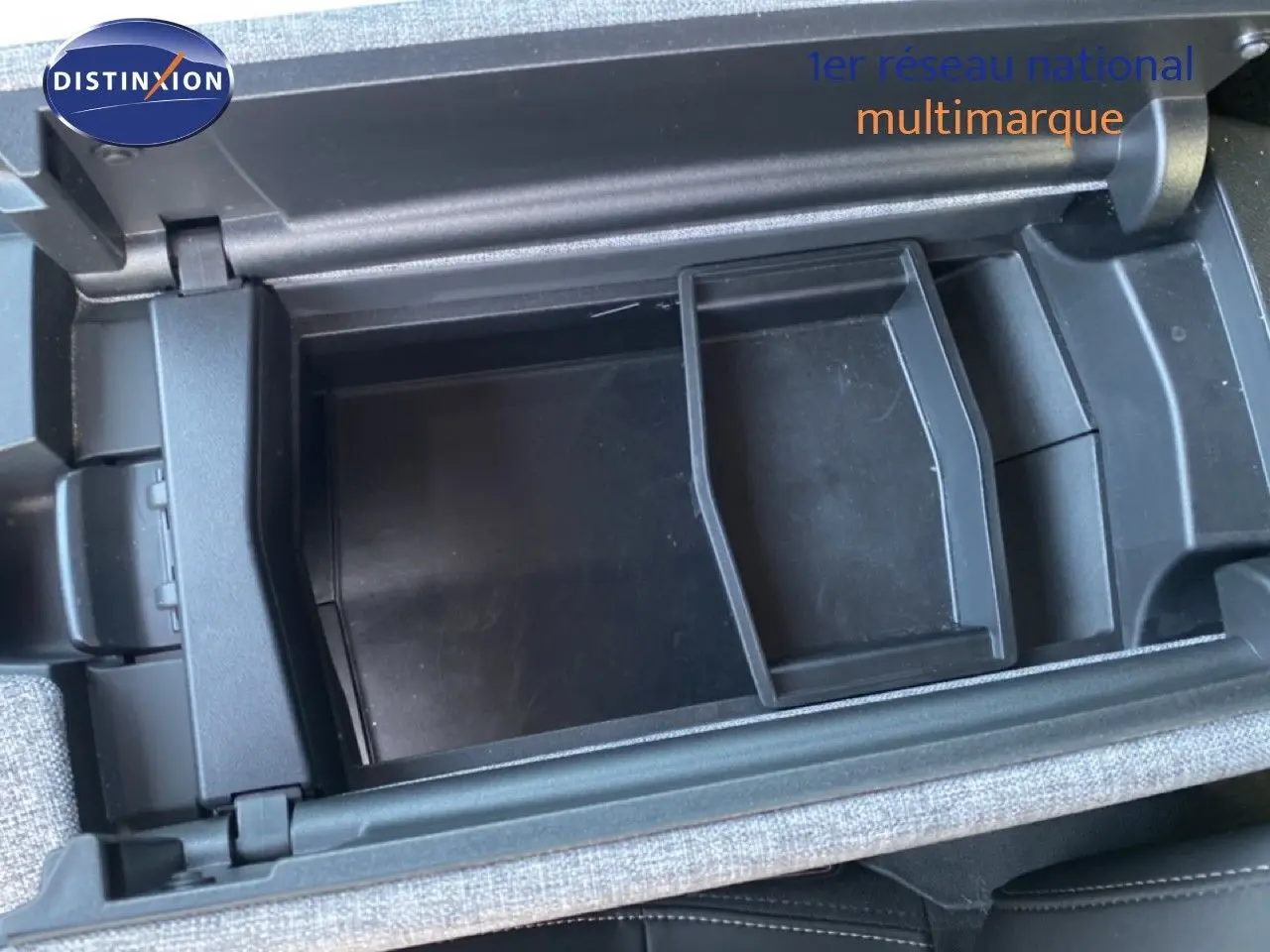 Vue en plongée sur le rangement central ouvert du Peugeot 5008 Hybrid 145ch Allure 2025, intérieur gris noir.