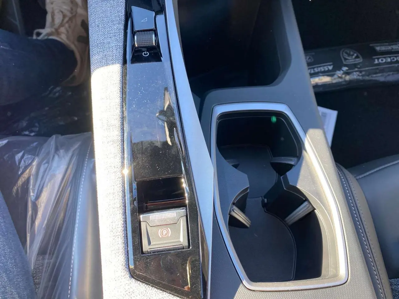 Gros plan sur la console centrale du Peugeot 3008 noir 2025, avec frein de stationnement électrique et porte-gobelets.