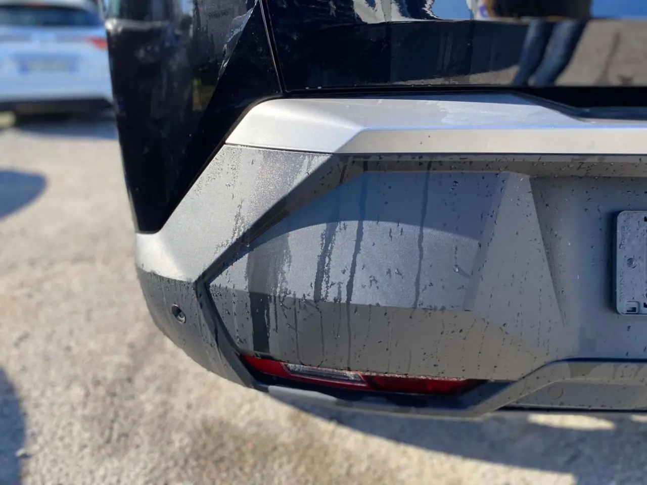 Gros plan sur le pare-chocs arrière droit noir métallisé du Peugeot 3008 1.2i Hybrid 2025 avec feu antibrouillard intégré.