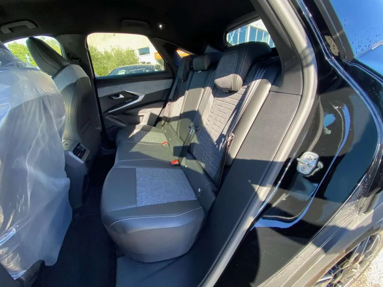 Vue intérieure côté droit des sièges arrière du Peugeot 3008 noir 2025, avec sellerie mixte tissu et cuir.