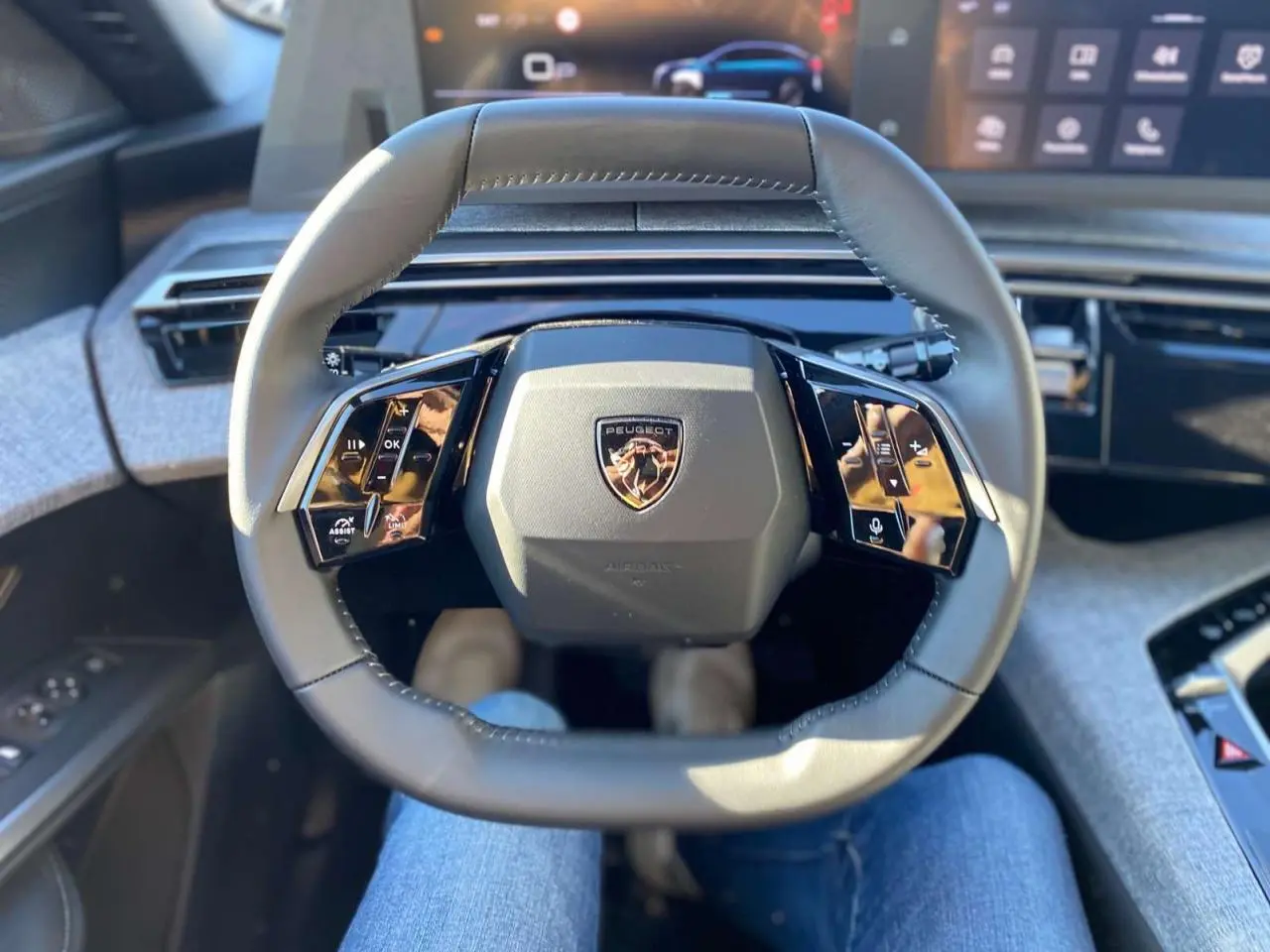 Vue intérieure centrée sur le volant cuir noir du Peugeot 3008 2025 avec commandes tactiles et logo au centre.