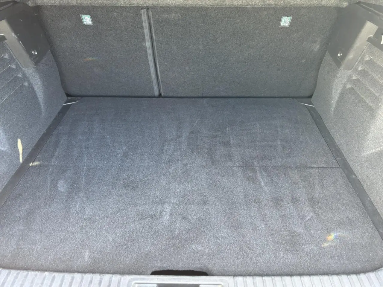 Coffre spacieux vu de face, revêtement gris foncé, intérieur propre sans chargement visible.