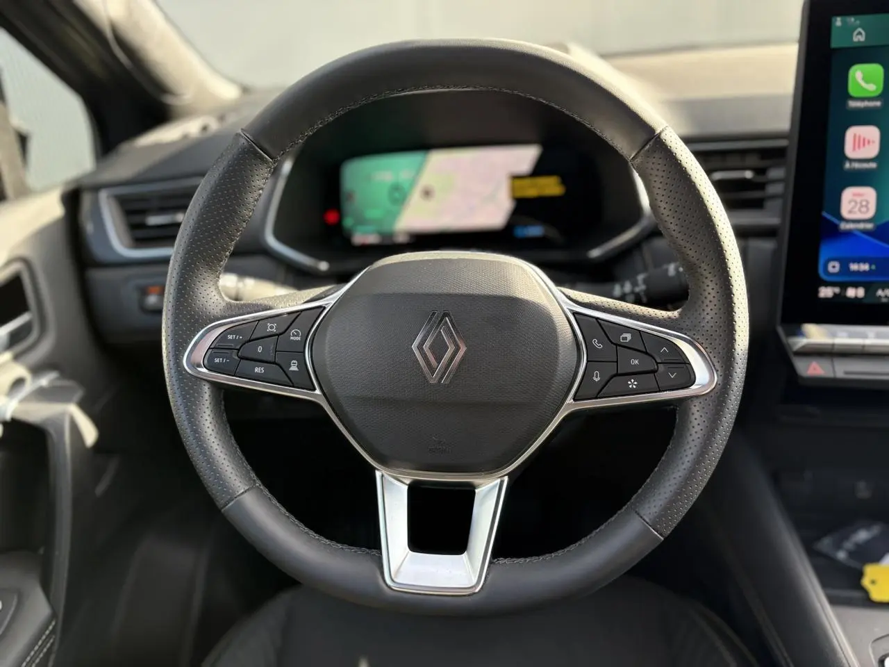 Volant noir perforé de Renault Symbioz 2025 avec commandes intégrées, tableau de bord numérique et écran tactile latéral visible.