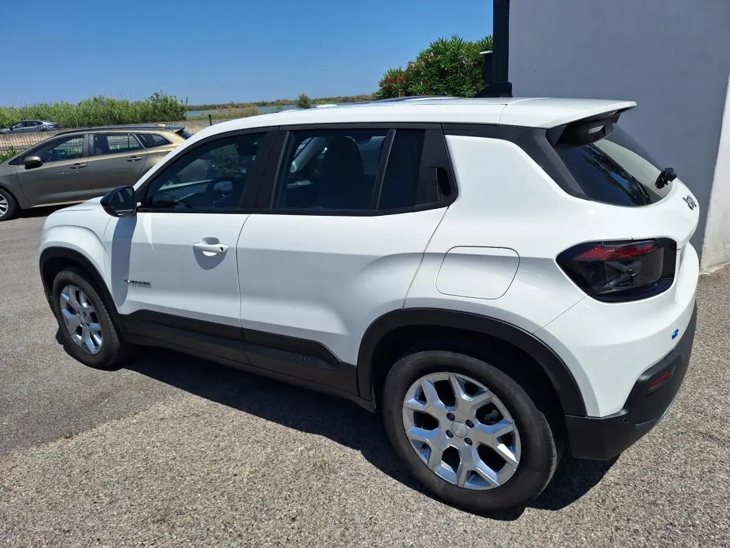 Jeep Avenger électrique blanc en vue 3/4 arrière droit, avec jantes alliage 17 pouces et vitres teintées.