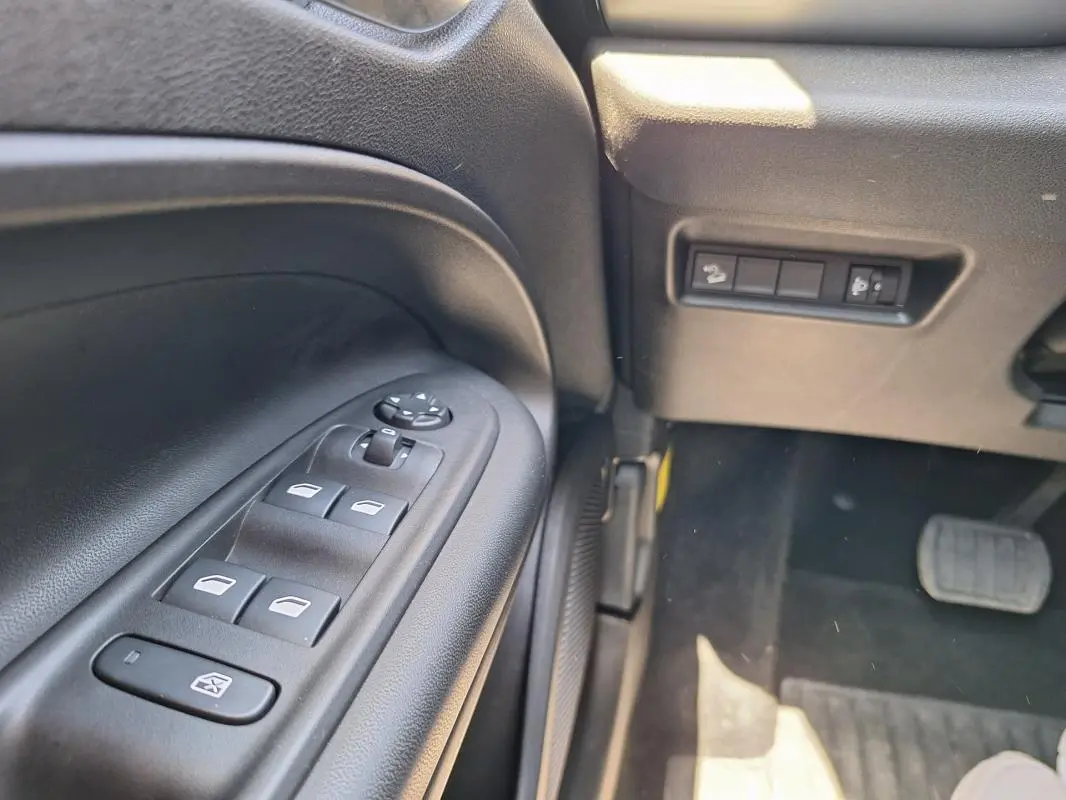 Vue rapprochée du panneau de commandes des vitres électriques côté gauche intérieur du Jeep Avenger blanc électrique 2025.