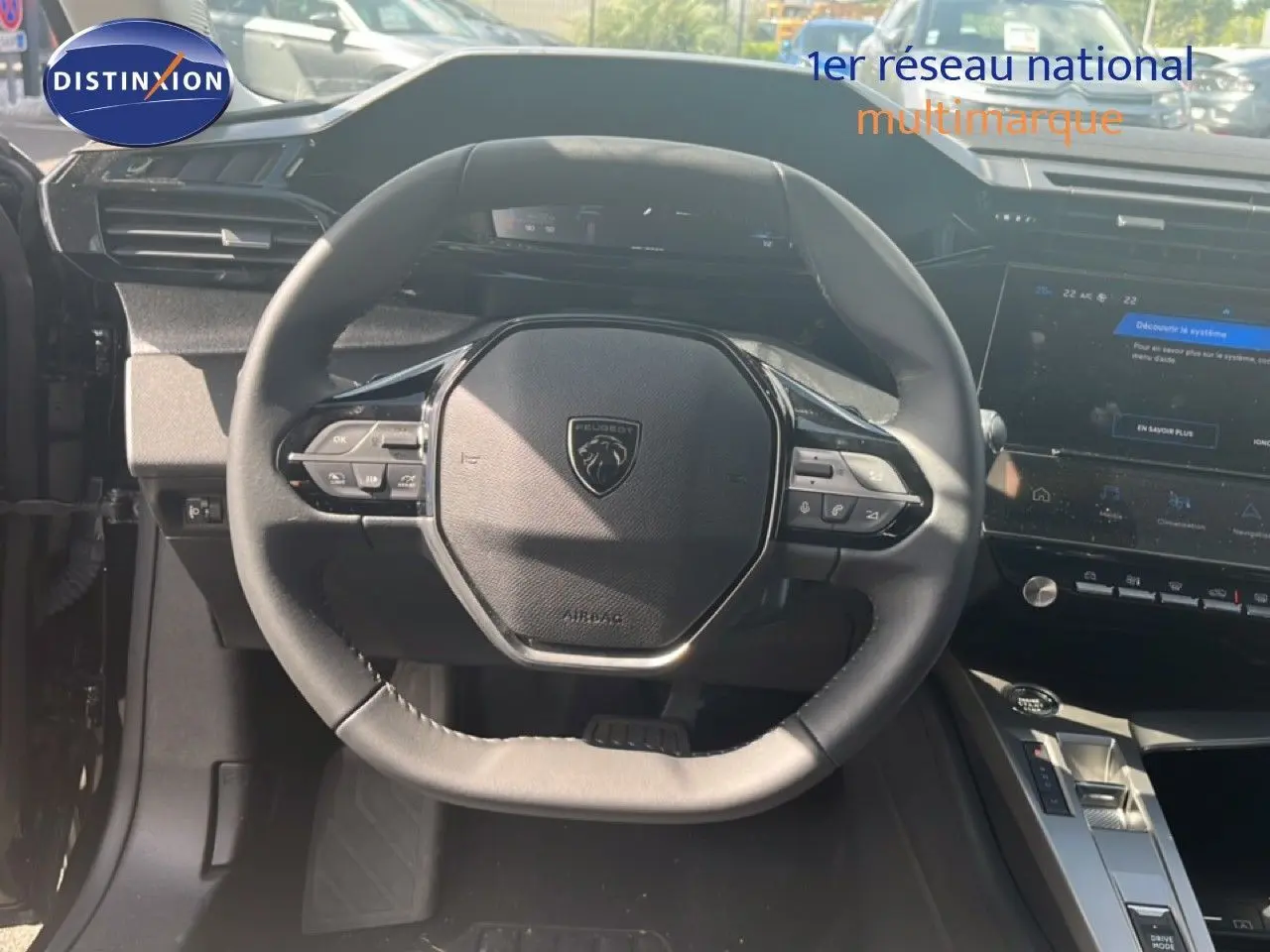 Vue intérieure centrée sur le volant noir de la Peugeot 308 Hybrid 145ch 2025 avec tableau de bord et console tactile visibles.