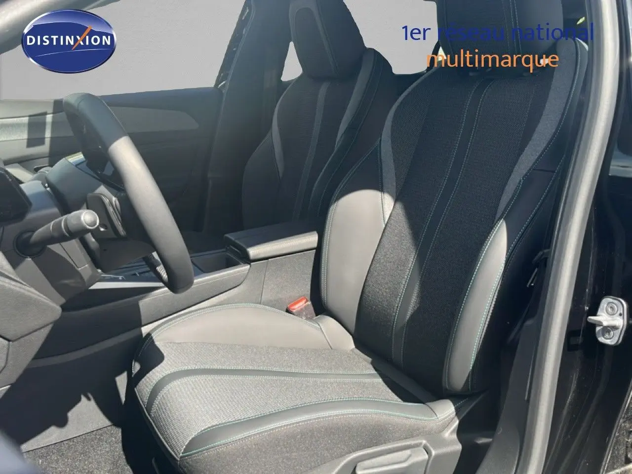 Vue intérieure côté conducteur de la Peugeot 308 Hybrid 2025, siège bi-matière gris noir avec surpiqûres vertes.