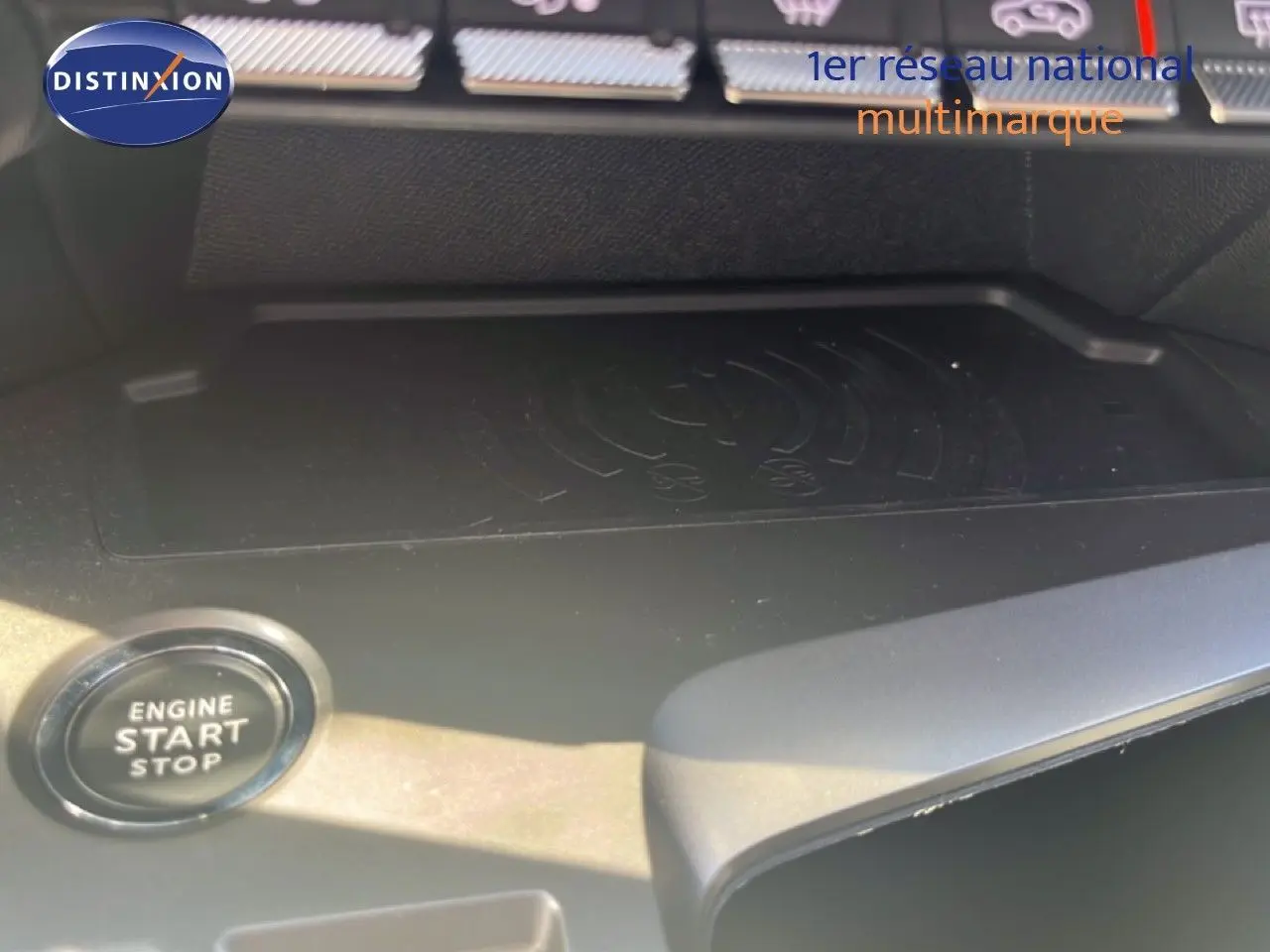 Gros plan sur le bouton start/stop et la zone de recharge sans fil dans l'habitacle d'une Peugeot 308 noir métal.