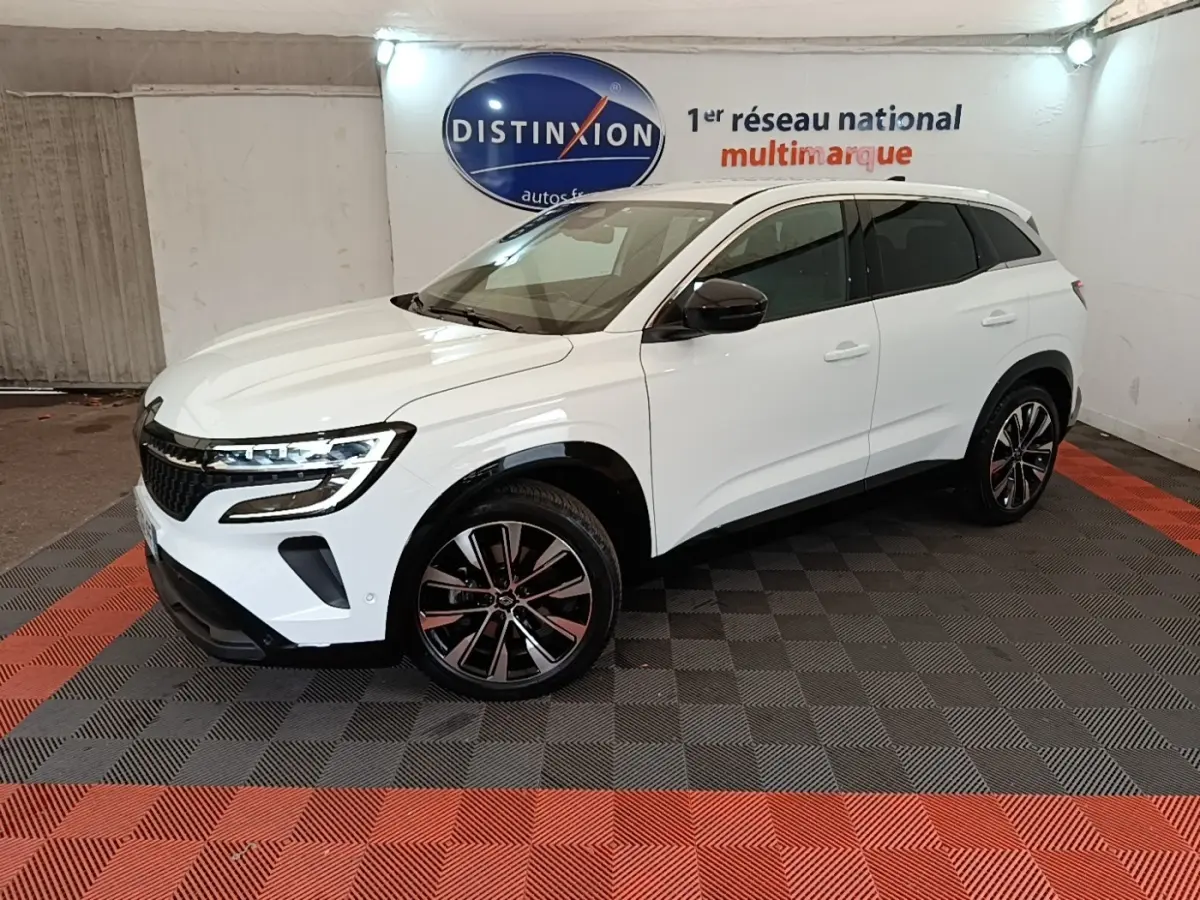 Renault Austral blanc en 3/4 avant droit, avec jantes noires et toit blanc dans un showroom intérieur.
