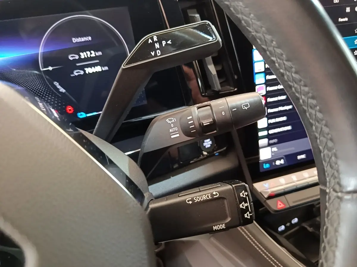 Gros plan intérieur sur les commandes au volant du Renault Austral blanc, avec écran tactile et affichage numérique.