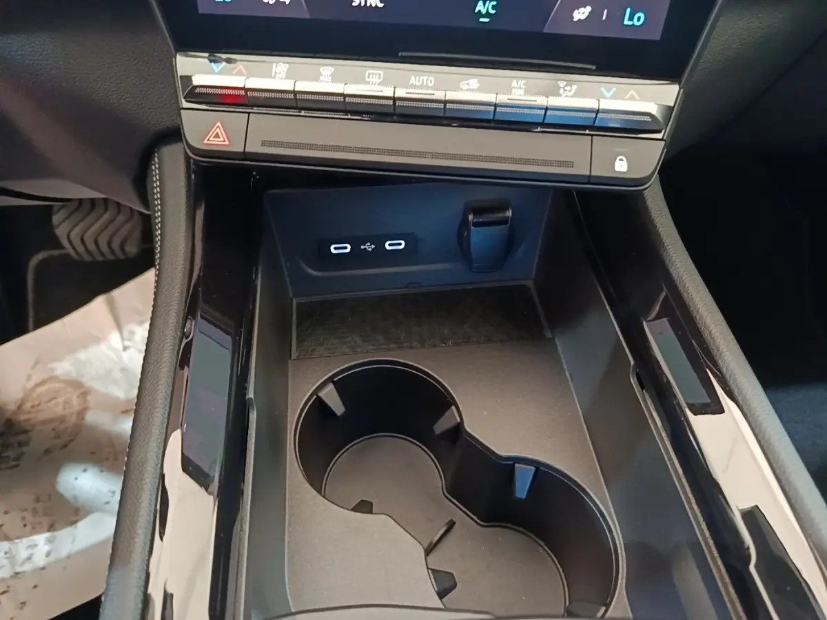 Gros plan sur la console centrale noire du Renault Austral blanc, avec porte-gobelets et ports USB-C visibles.