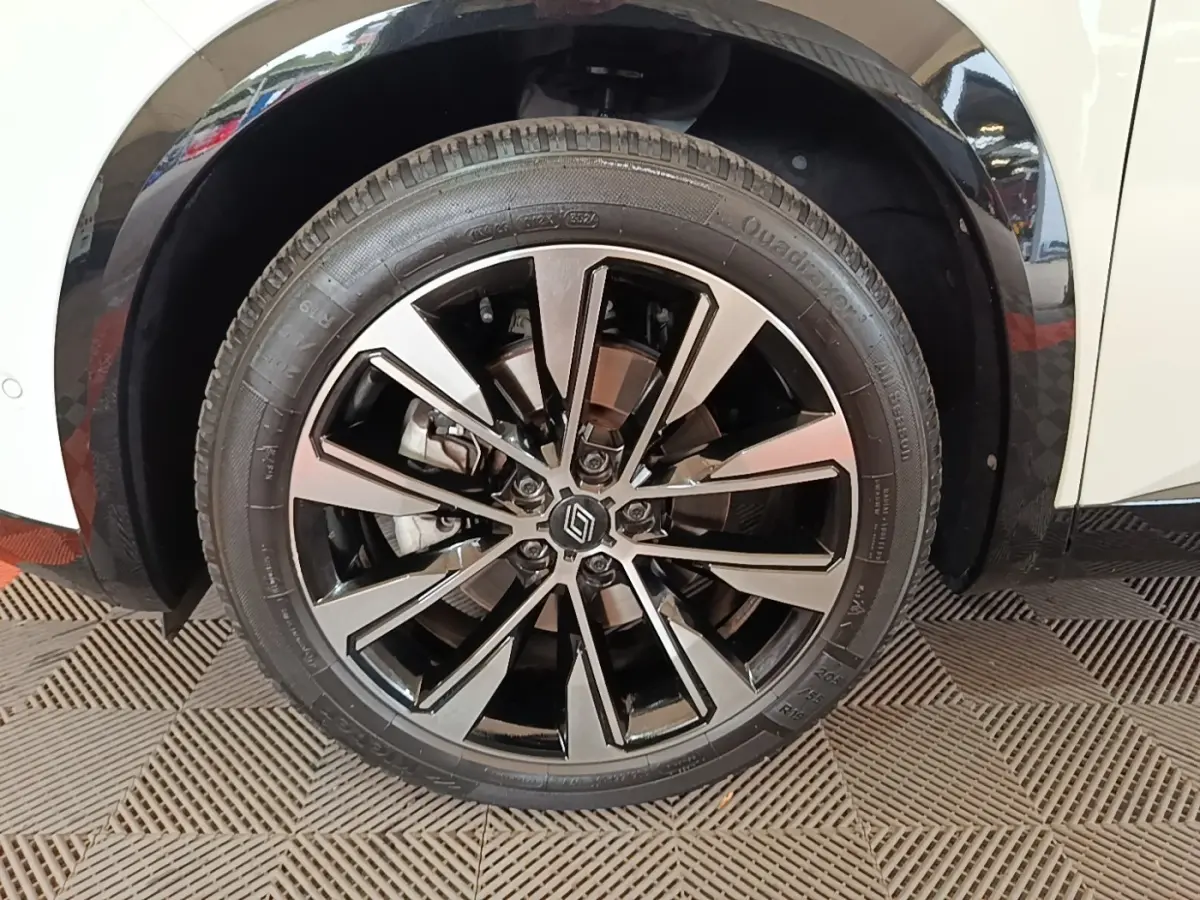Gros plan sur la roue avant gauche du Renault Austral blanc, avec jante alliage noir et argentée au design moderne.
