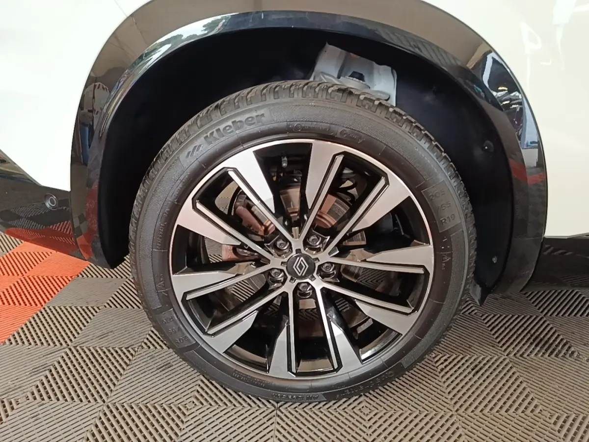 Gros plan sur la roue avant droite du Renault Austral blanc, mettant en valeur la jante alliage noire et argentée.