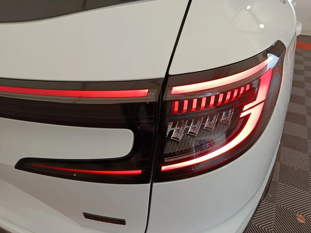 Gros plan sur le feu arrière droit allumé du Renault Austral blanc, avec bande lumineuse rouge distinctive.