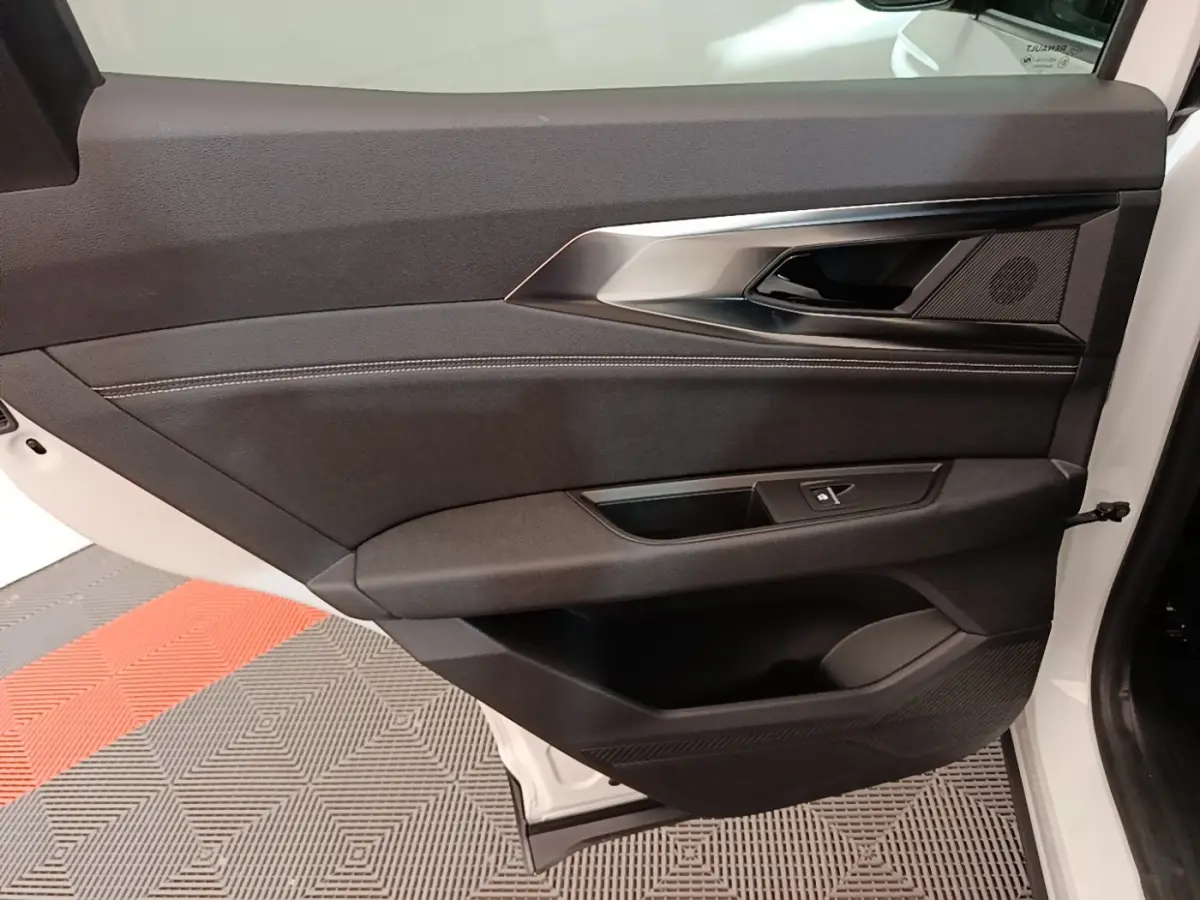 Vue intérieure du panneau de porte arrière droite noire avec insert argenté sur Renault Austral blanc 2023.