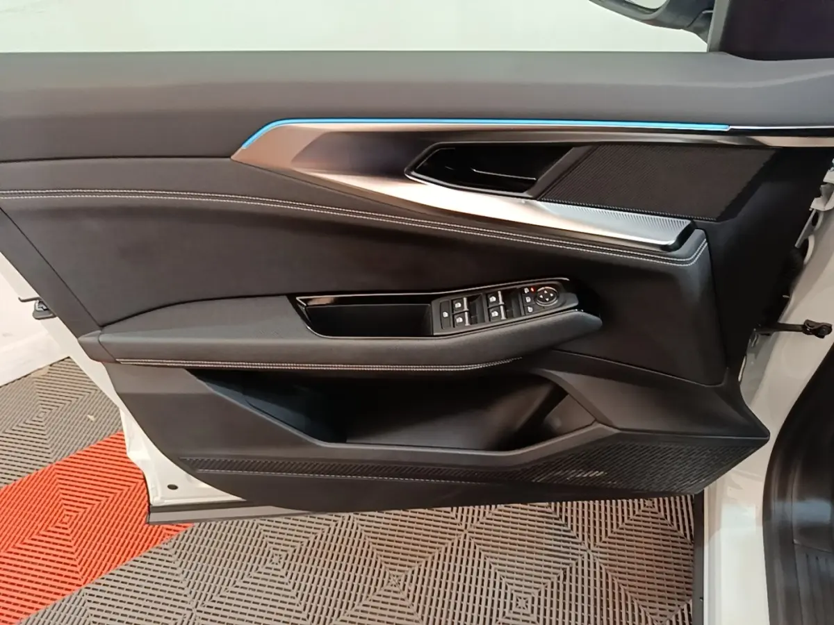 Vue latérale du panneau de porte avant gauche blanc du Renault Austral 2023 avec commandes électriques et bandeau lumineux bleu.