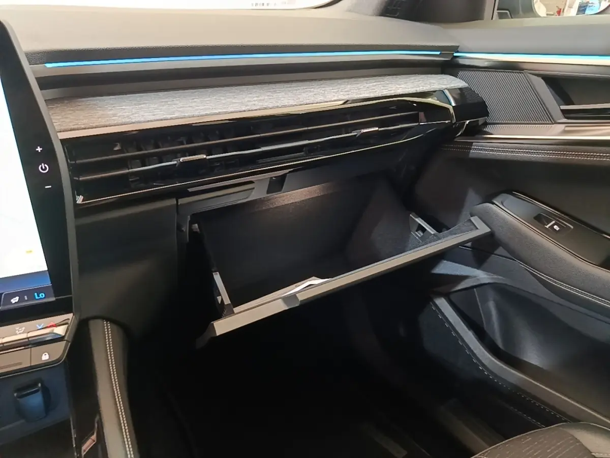 Intérieur Renault Austral 2023, vue côté passager sur la boîte à gants ouverte et tableau de bord noir avec inserts bois.