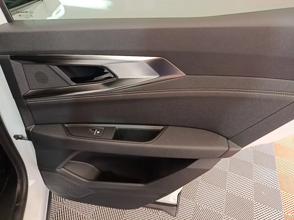 Vue rapprochée de la porte avant gauche noire du Renault Austral blanc, avec poignée et commandes de fenêtre intégrées.