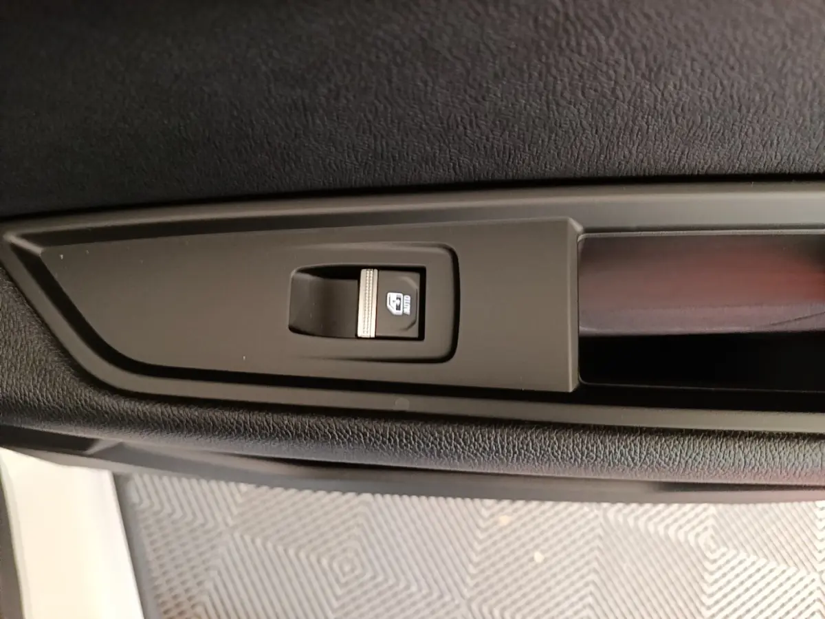 Gros plan sur le bouton de commande de lève-vitre électrique côté porte avant d’un Renault Austral blanc.