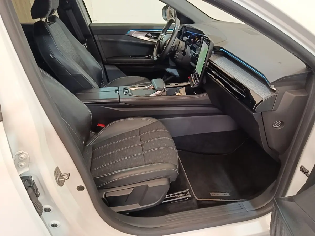 Vue intérieure côté passager avant du Renault Austral blanc, avec sièges noirs et écran tactile vertical lumineux.