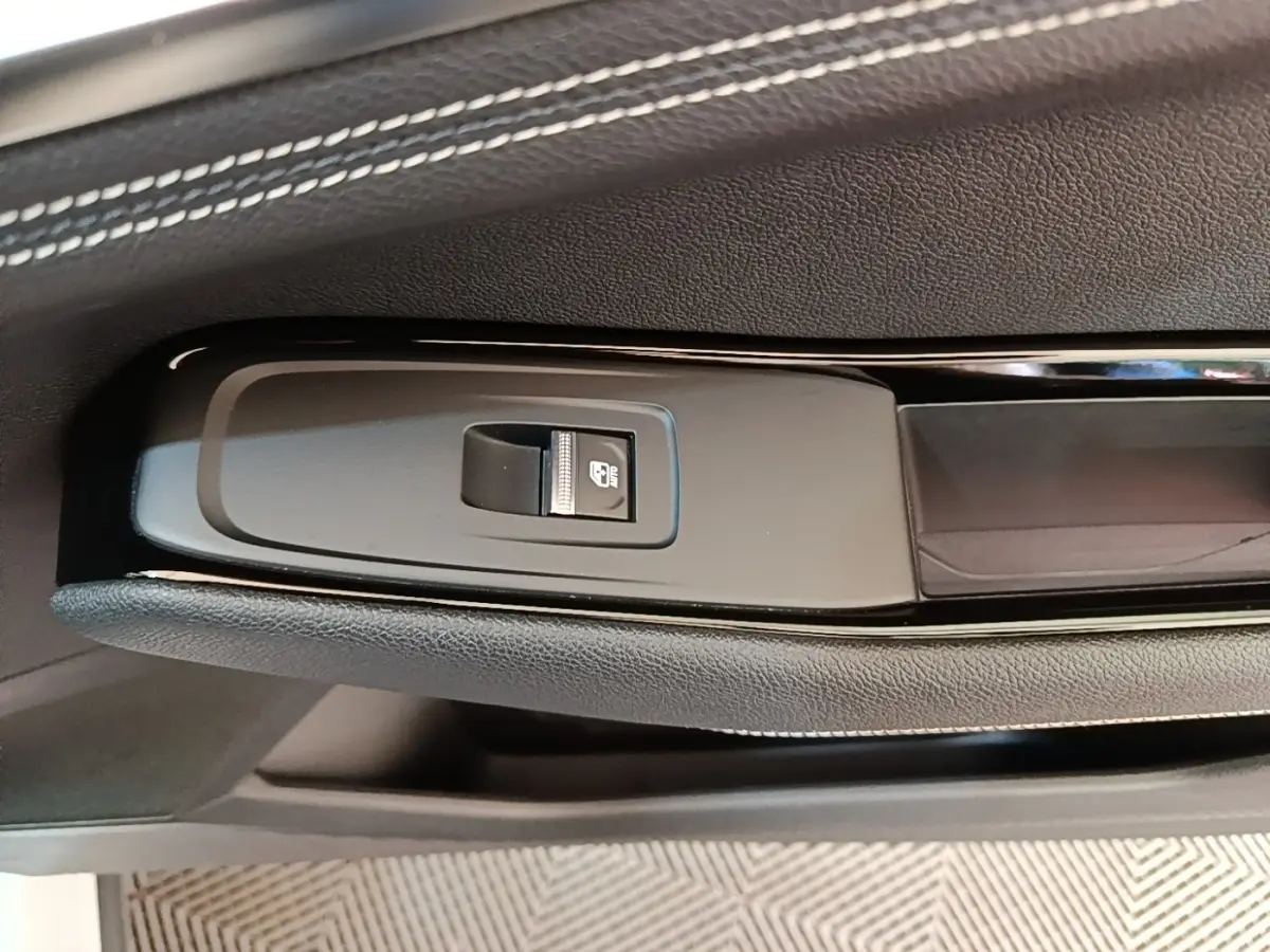 Gros plan sur la commande de verrouillage électrique sur la porte intérieure noire du Renault Austral blanc.