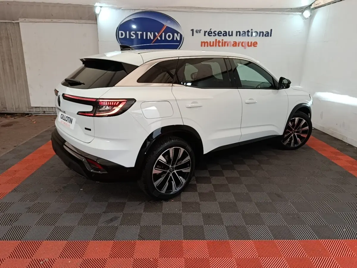 Vue 3/4 arrière droite du Renault Austral blanc 2023 avec feux LED et toit noir contrastant dans un showroom.