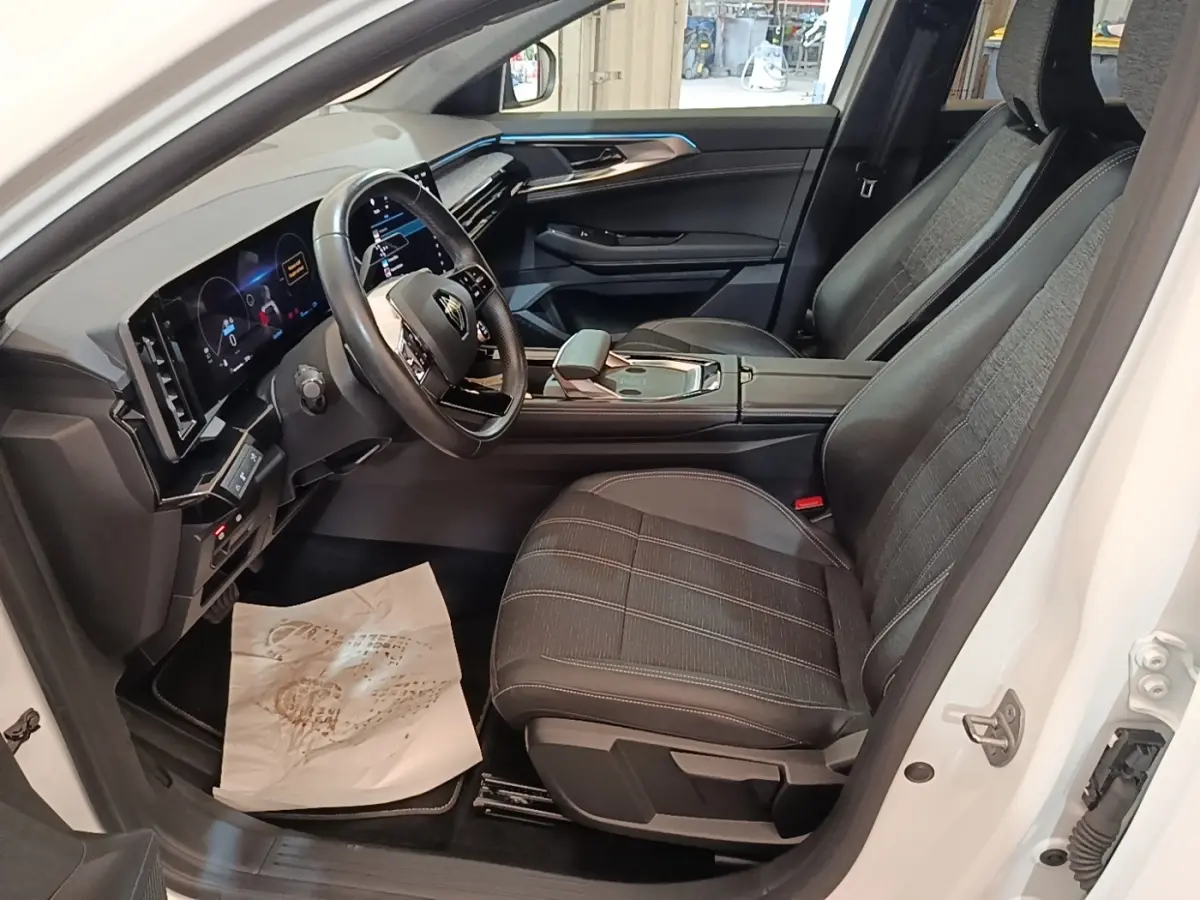 Vue intérieure côté conducteur du Renault Austral blanc 2023, avec tableau de bord digital et sièges tissu noir.
