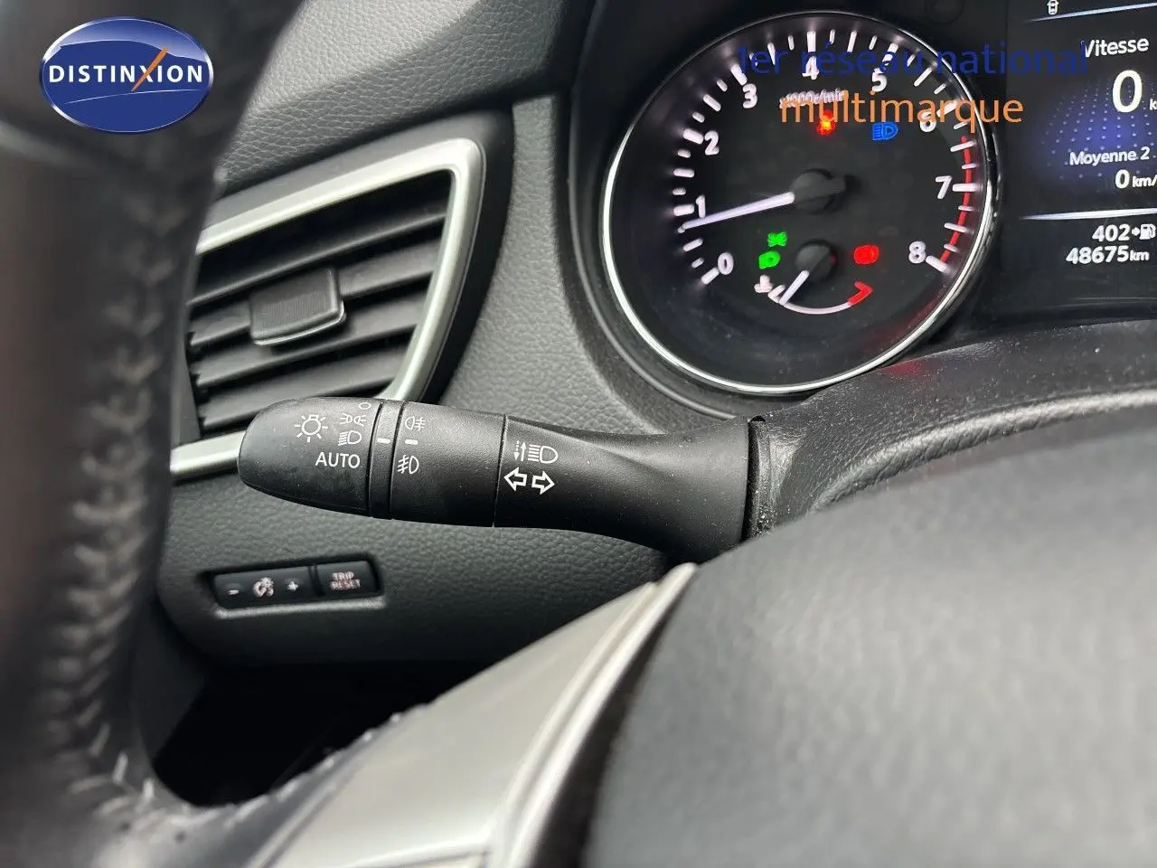Gros plan sur le commodo des phares et clignotants à gauche du volant, tableau de bord noir du Nissan Qashqai 2017.