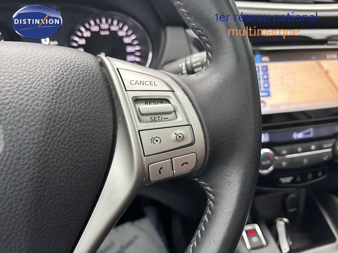 Gros plan sur le volant noir du Nissan Qashqai blanc glacier, avec commandes de régulateur de vitesse visibles.
