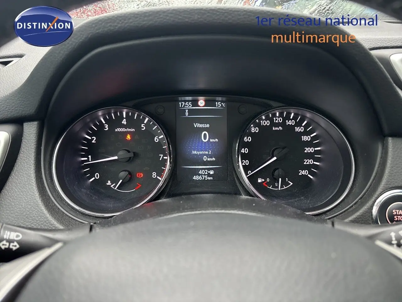 Vue rapprochée du tableau de bord du Nissan Qashqai blanc glacier, affichant le compteur et l'écran digital.