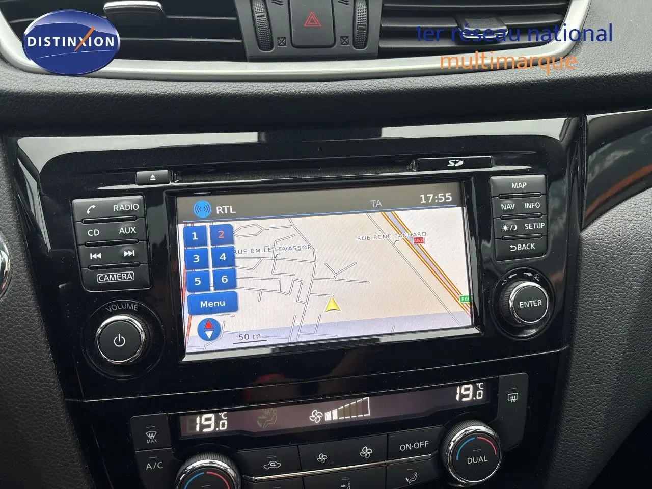 Vue rapprochée de la console centrale du Nissan Qashqai blanc glacier, mettant en valeur l'écran tactile GPS et les commandes de climatisation.