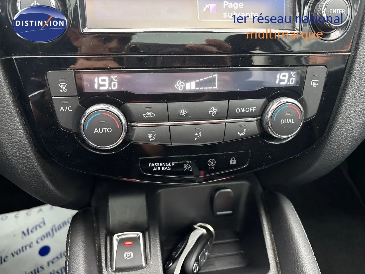 Tableau de bord du Nissan Qashqai 2017 en gros plan, montrant la climatisation automatique et les commandes centrales.