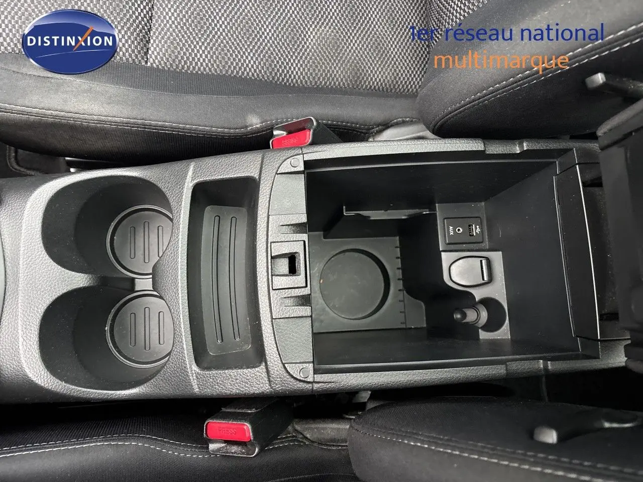 Vue plongeante sur la console centrale noire du Nissan Qashqai 2017, avec porte-gobelets et compartiment ouvert.