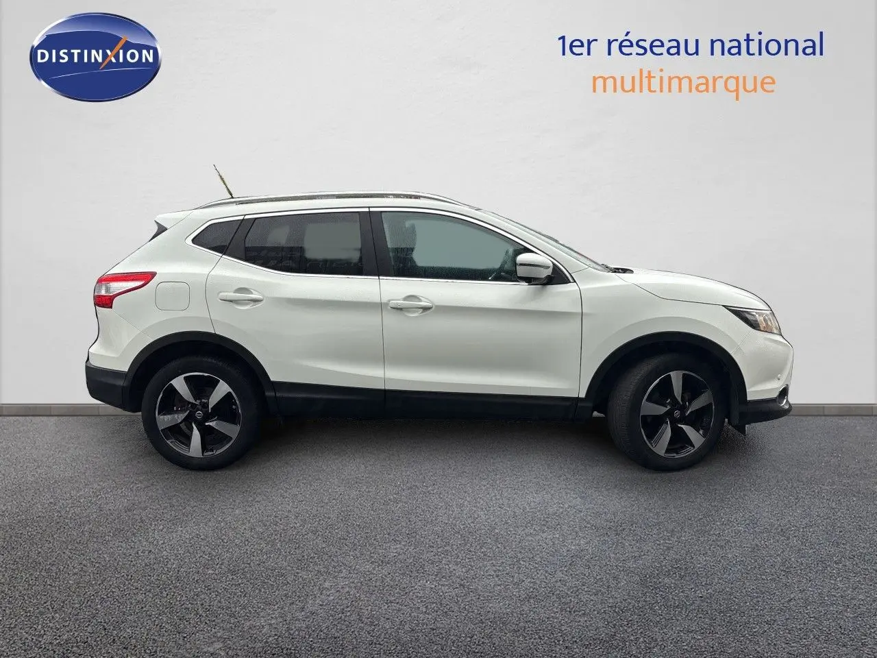 Nissan Qashqai blanc glacier vu de profil côté gauche sur fond neutre, avec jantes bi-ton et toit ouvrant.