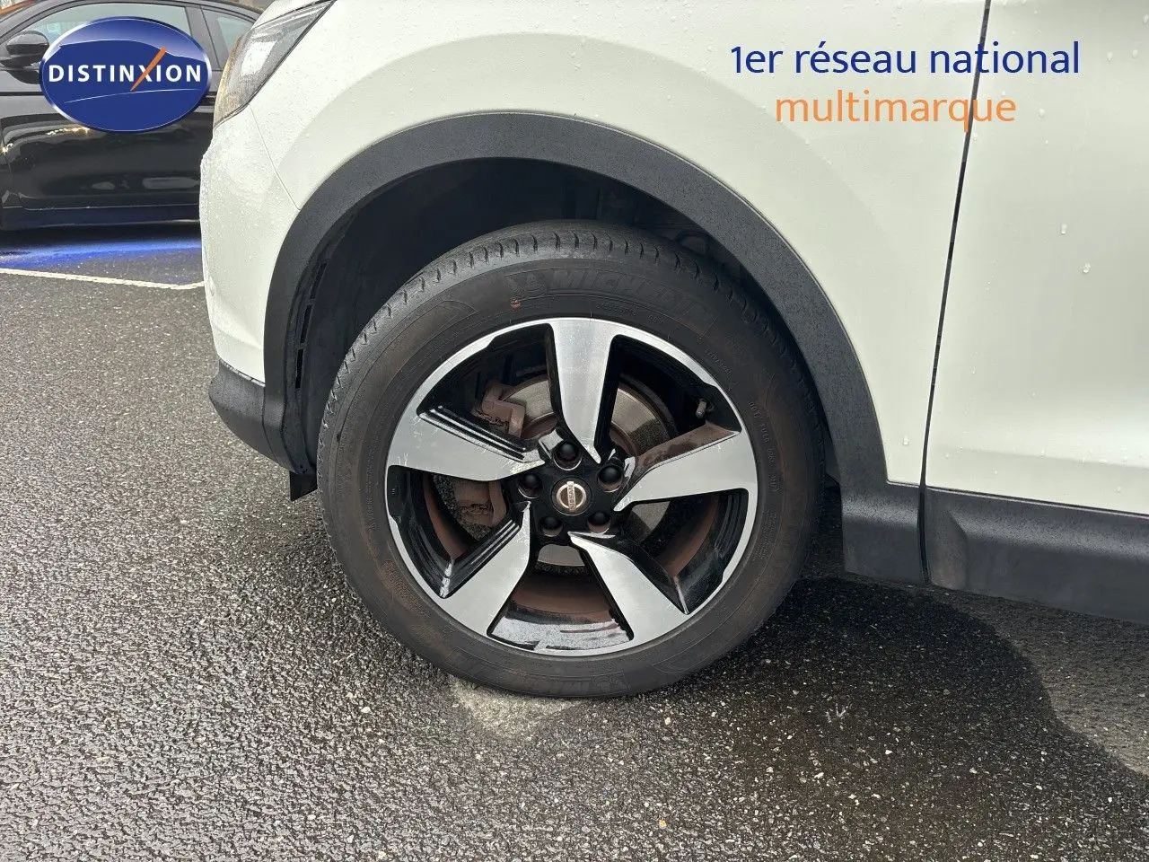 Gros plan sur la roue avant droite du Nissan Qashqai blanc glacier, avec jante alliage bi-ton distincte.